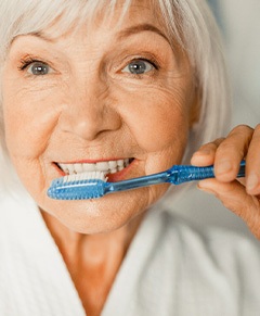 An older woman brushing her teeth in the morning