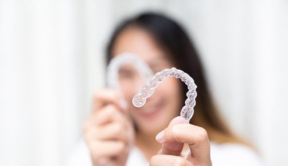 Patient smiling while holding clear aligners