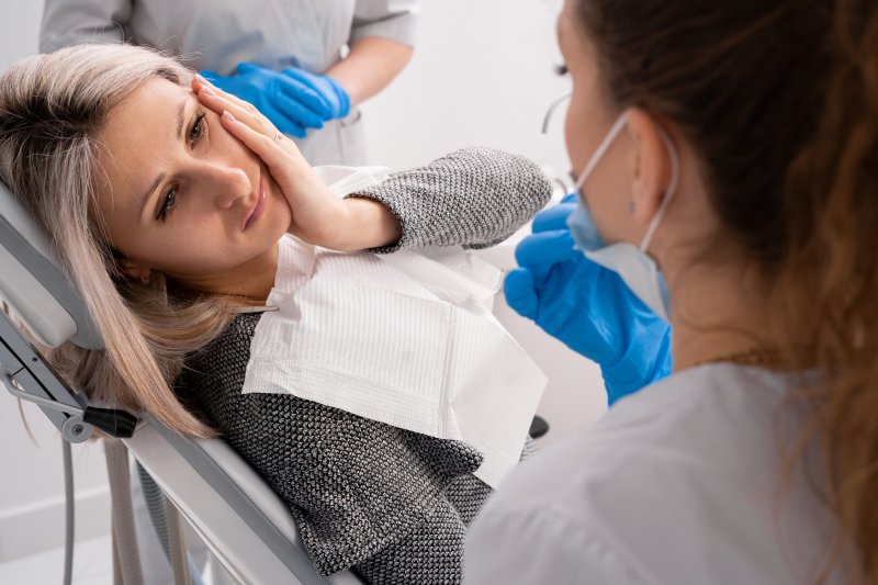 Pained lady looks at emergency dentist