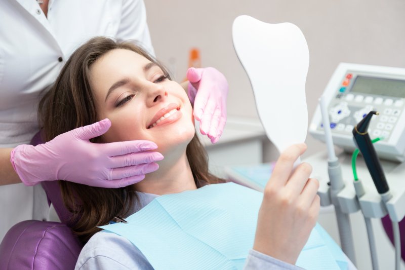 A young woman admiring her treated smile with a hand mirror